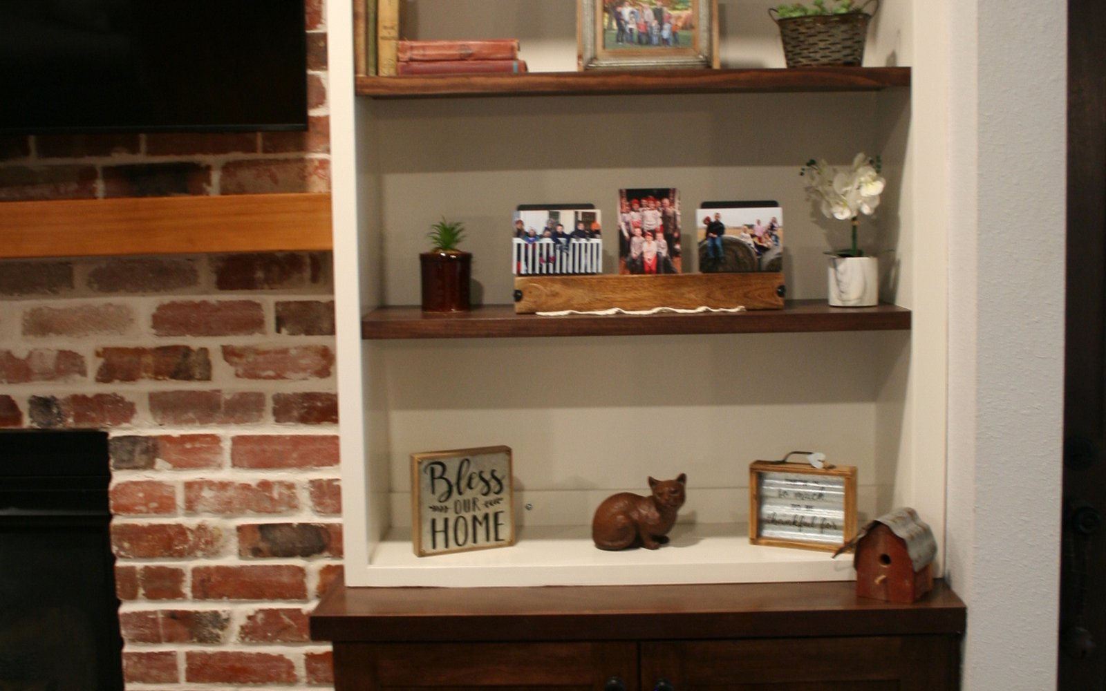 Custom dark base cabinet and open shelves fitted beside a brick fireplace