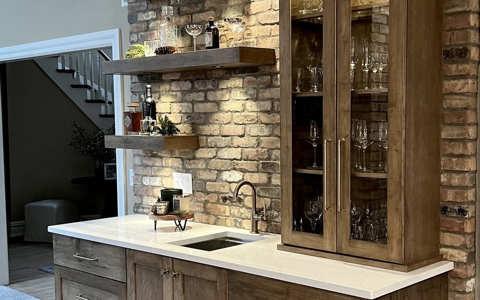 Rustic wet bar with natural wood cabinets, a stone wall, open shelves, and a fitted sink