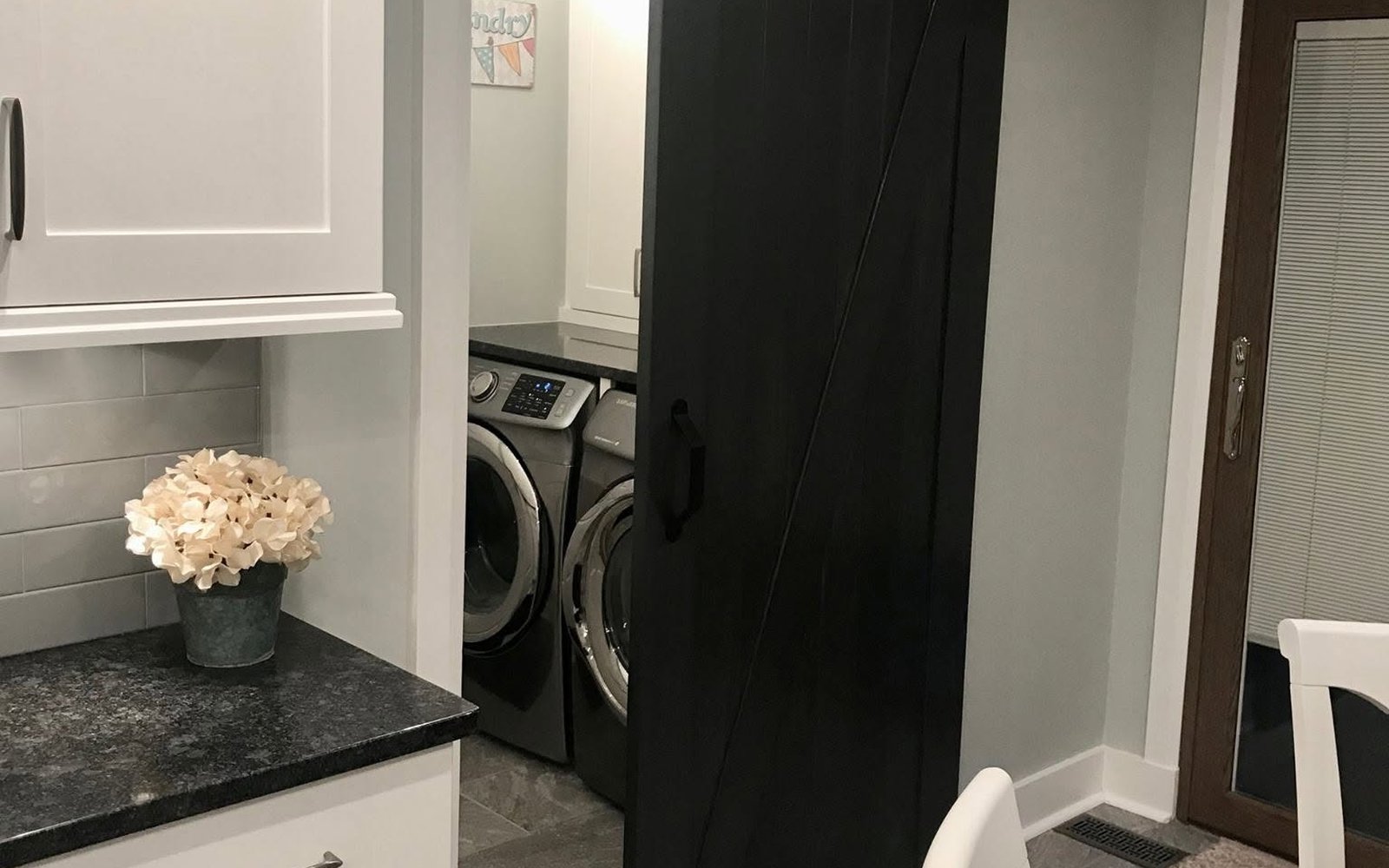 Laundry-room cabinetry and counter storage beside a black sliding barn door