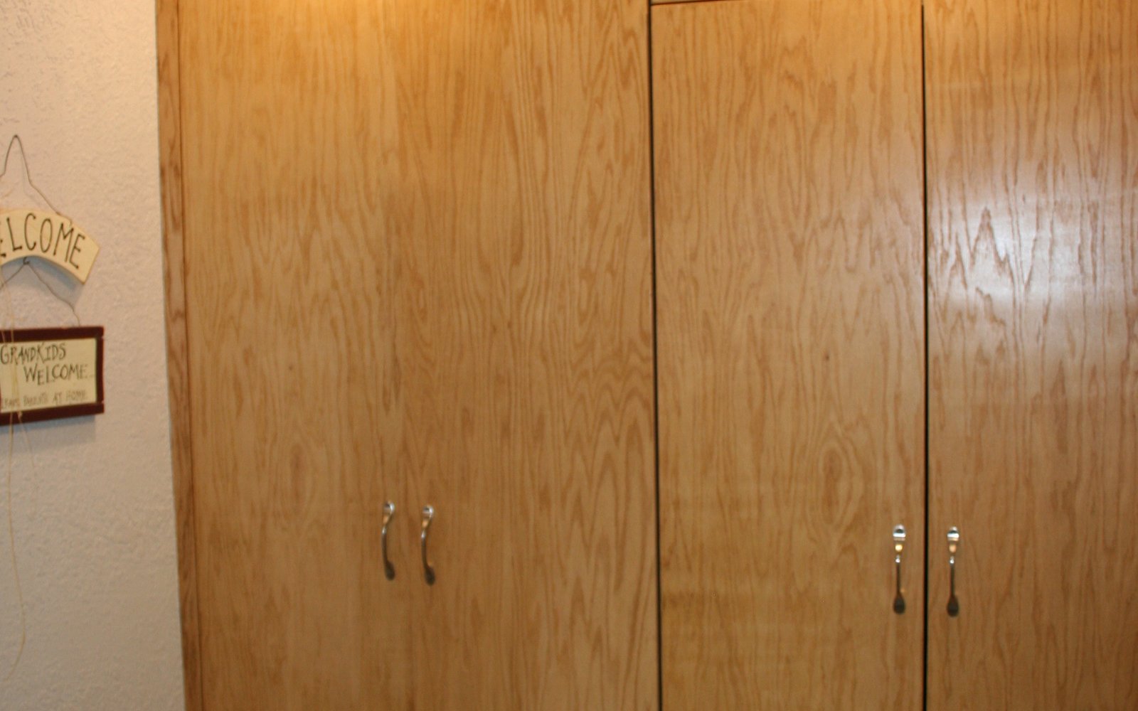 Tall light oak storage cabinets with simple metal pulls in a finished interior