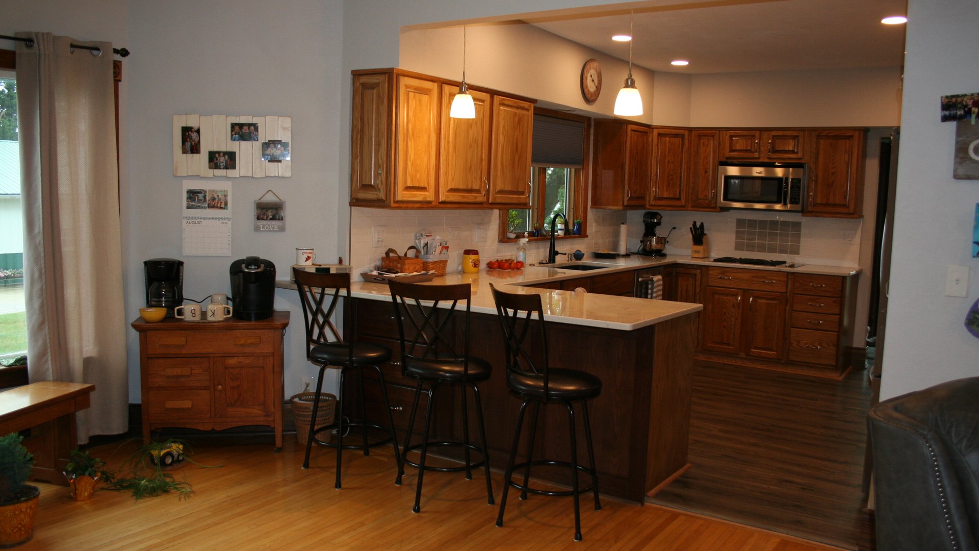 Completed warm oak kitchen with a peninsula, island seating, and full-height cabinetry