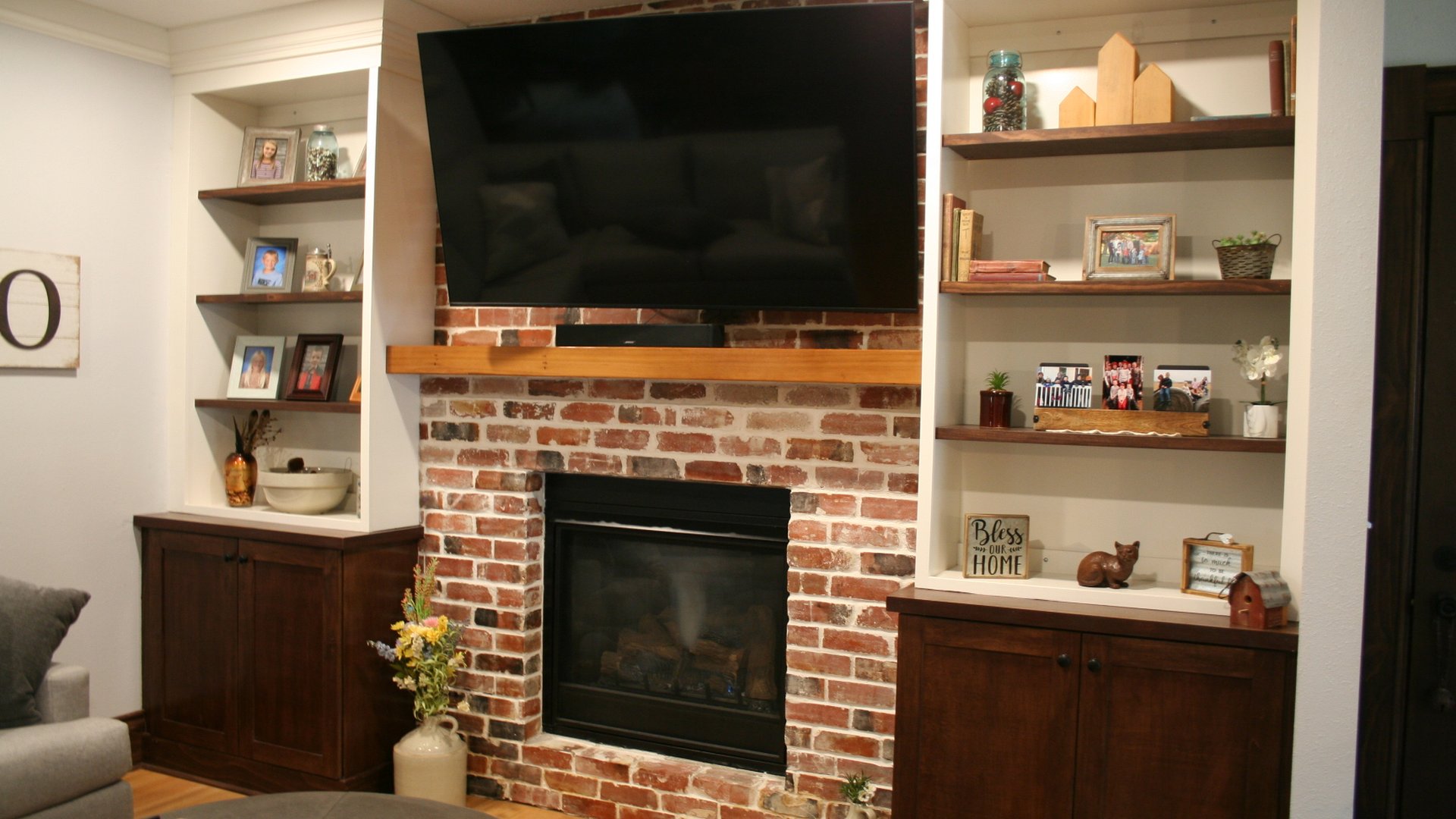 Living room built-ins with dark base cabinets and white shelves around a brick fireplace