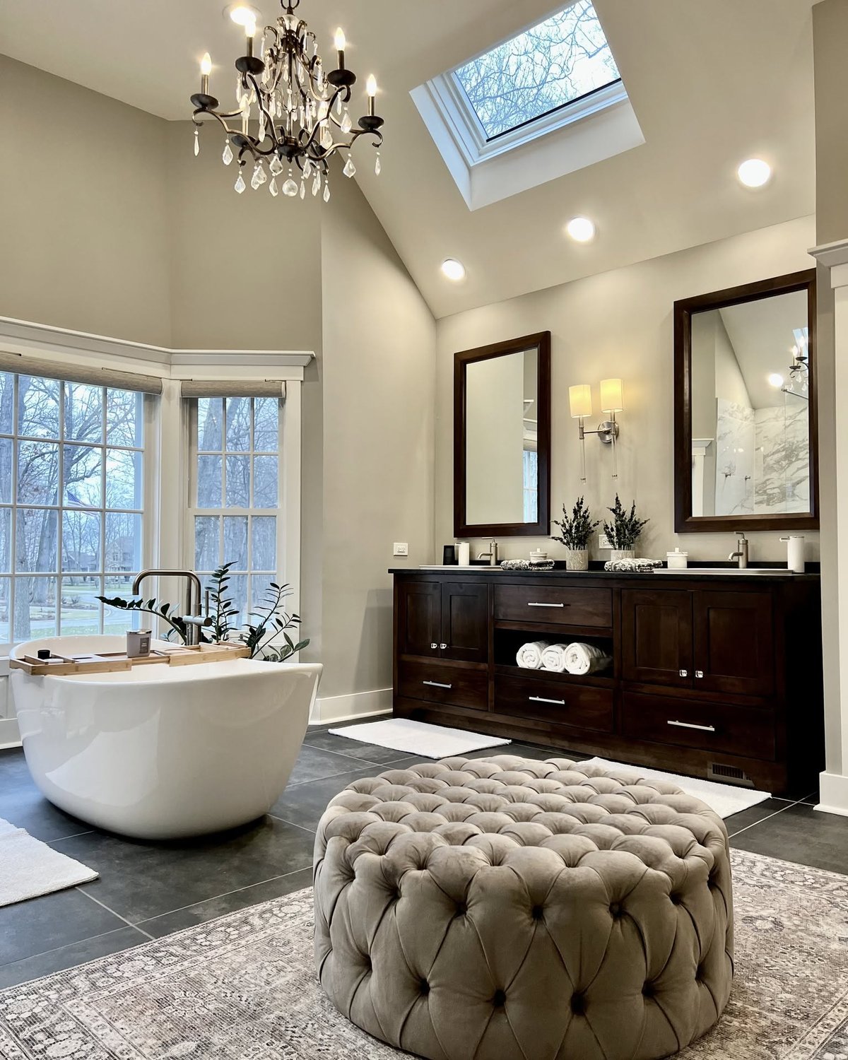Dark wood double bathroom vanity with drawers beside a freestanding tub and tall windows