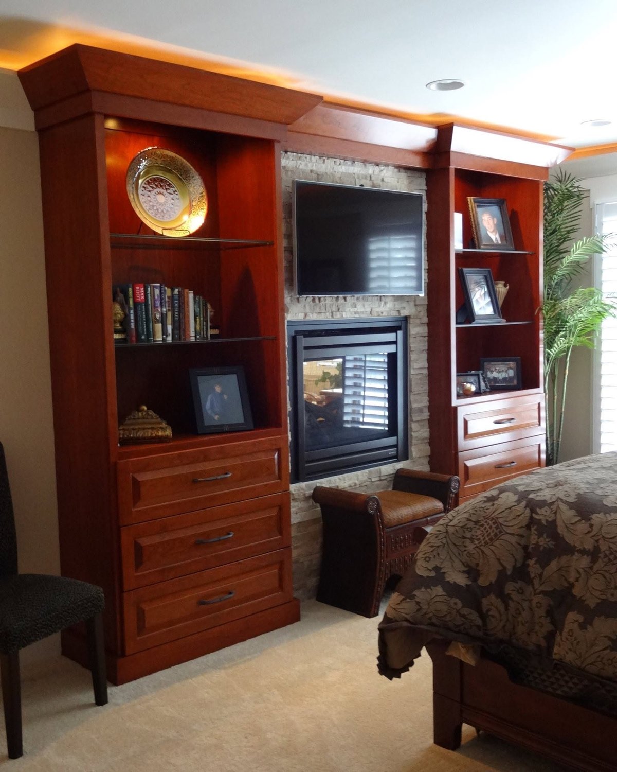 Stained wood entertainment built-in with drawers, shelves, a television, and a compact fireplace