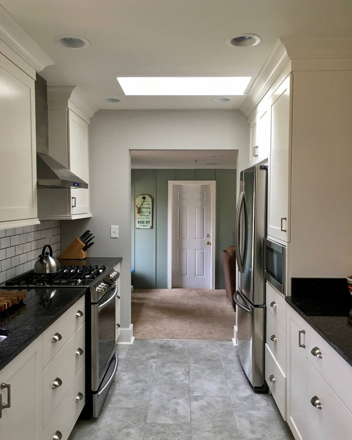 White galley kitchen cabinetry fitted around appliances and a narrow central walkway