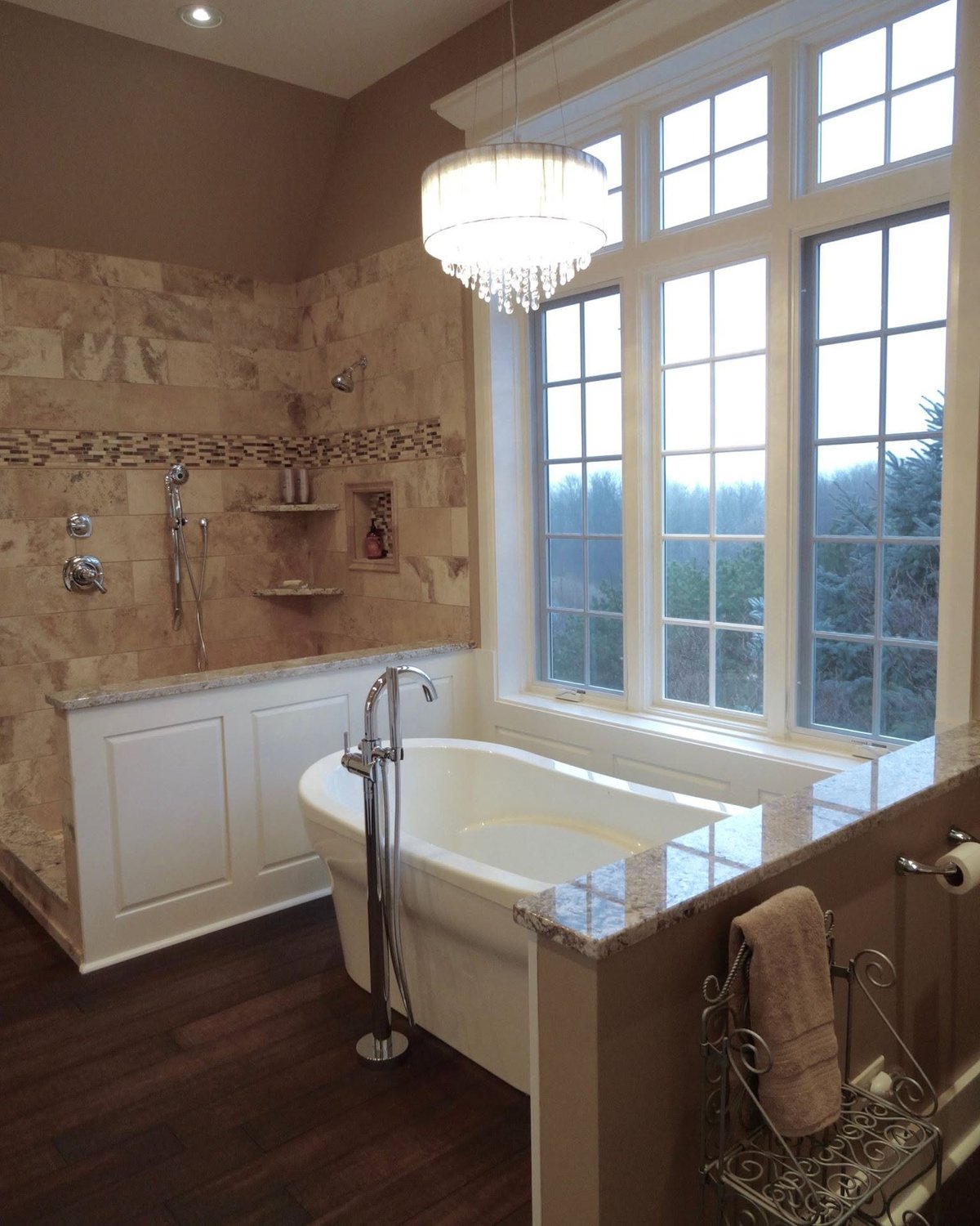 Tiled bathroom with custom white tub paneling beneath tall windows